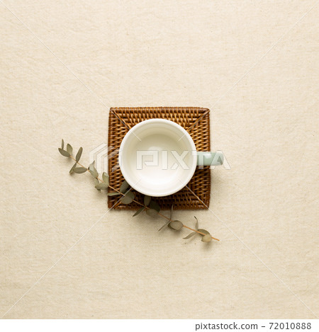 Empty mug cup with eucalyptus leaf on beige fabric background. top view Empty mug cup with eucalyptus leaf on beige fabric background. top view 72010888