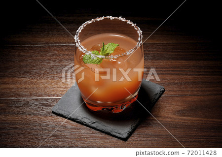 Pink salty dog with mint with salt on the edge of the glass placed on the slate plate Pink salty dog with mint with salt on the edge of the glass placed on the slate plate 72011428