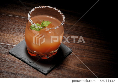 Pink salty dog with mint with salt on the edge of the glass placed on the slate plate Pink salty dog with mint with salt on the edge of the glass placed on the slate plate 72011432