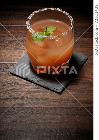 Pink salty dog with mint with salt on the edge of the glass placed on the slate plate Pink salty dog with mint with salt on the edge of the glass placed on the slate plate 72011435