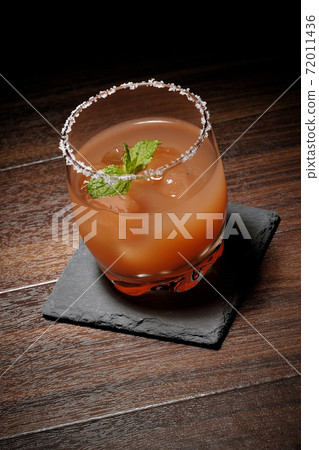 Pink salty dog with mint with salt on the edge of the glass placed on the slate plate Pink salty dog with mint with salt on the edge of the glass placed on the slate plate 72011436
