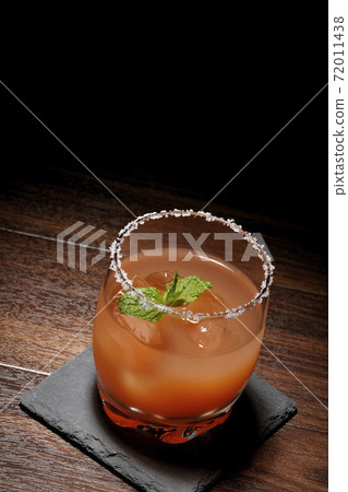Pink salty dog with mint with salt on the edge of the glass placed on the slate plate Pink salty dog with mint with salt on the edge of the glass placed on the slate plate 72011438