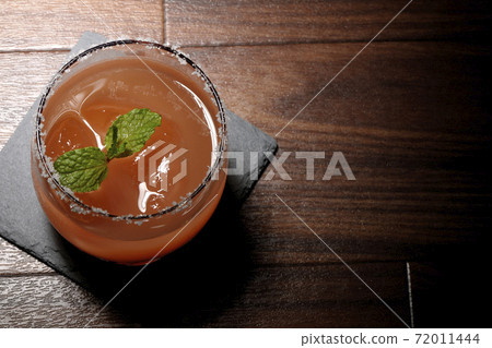Pink salty dog with mint (overhead view) with salt on the edge of the glass placed on the slate plate Pink salty dog with mint (overhead view) with salt on the edge of the glass placed on the slate plate 72011444