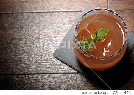 Pink salty dog with mint (overhead view) with salt on the edge of the glass placed on the slate plate 72011445