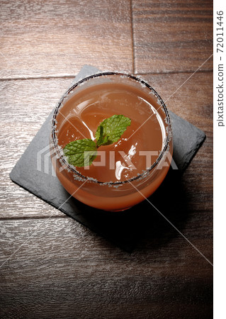 Pink salty dog with mint (overhead view) with salt on the edge of the glass placed on the slate plate Pink salty dog with mint (overhead view) with salt on the edge of the glass placed on the slate plate 72011446