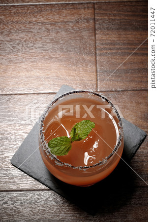 Pink salty dog with mint (overhead view) with salt on the edge of the glass placed on the slate plate Pink salty dog with mint (overhead view) with salt on the edge of the glass placed on the slate plate 72011447