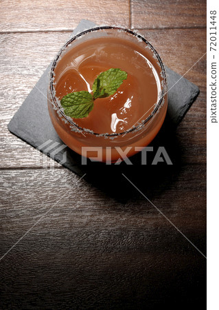 Pink salty dog with mint (overhead view) with salt on the edge of the glass placed on the slate plate Pink salty dog with mint (overhead view) with salt on the edge of the glass placed on the slate plate 72011448