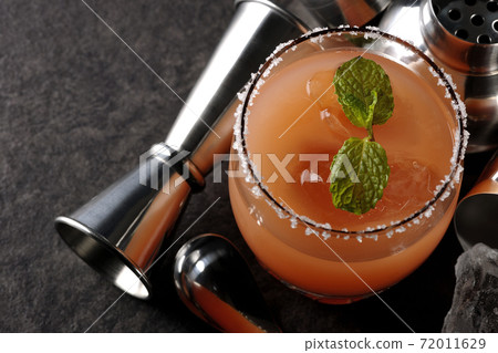 Salty dog with mint with salt on the edge of the glass, cocktail shaker and major cup 72011629