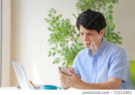 一名商人，困惑的表情，看著智能手機 72012862