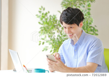 A businessman who is a little surprised to see a smartphone A businessman who is a little surprised to see a smartphone 72012869
