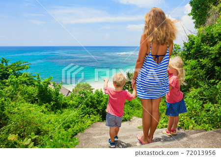 Mother, kids look at sea surf on white sand beach Mother, kids look at sea surf on white sand beach 72013956