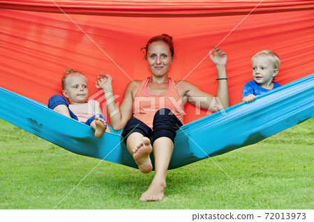 Funny kids with young mother chilling in swinging hammock Funny kids with young mother chilling in swinging hammock 72013973