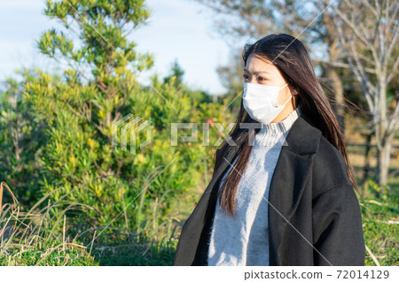 A woman wearing a mask and taking a walk in the park A woman wearing a mask and taking a walk in the park 72014129