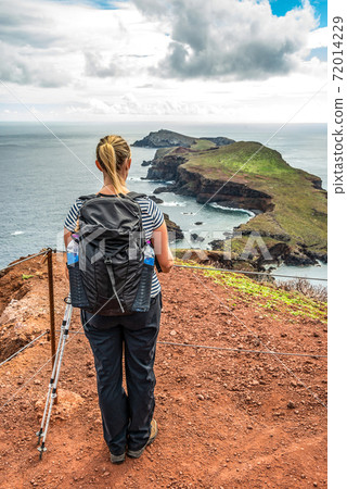 Girl hiking rocky cliffs clear near water of Atlantic Ocean bay Ponta de Sao Lourenco, the island of Madeira, Portugal 72014229