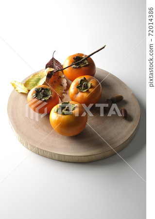 Photographed persimmons, acorns and fallen leaves on a log cutting board on a white background 72014386