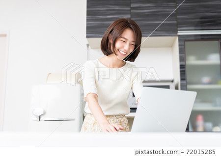 觀看一台計算機的婦女在廚房裡 72015285