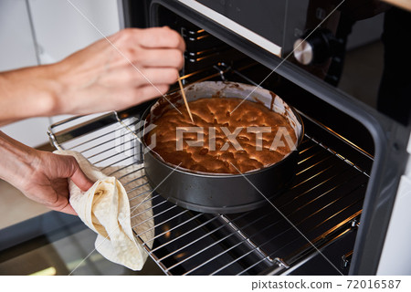 Housewife prepare cake in kitchen. Homemade cake baking in oven 72016587