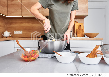 Woman in kitchen cooking a cake. Hands beat the dough with mixer 72016588