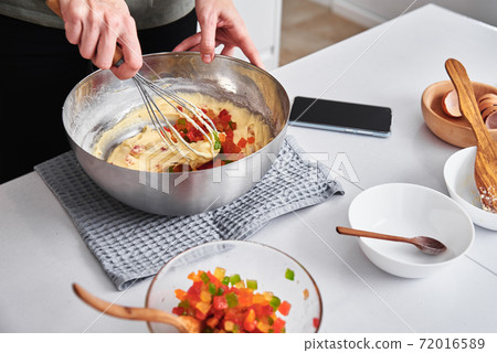 Woman in kitchen cooking a cake. Hands beat the dough with mixer 72016589
