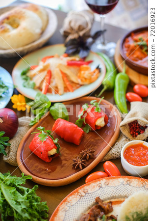 Muslim Ramadan iftar family dinner. Flat-lay of people feasting over table with Middle East food. Dates, dolma, kebab, flatbread, pide, borek, sweet, salad, top view. Ramazan fasting Turkish cuisine. 72016923