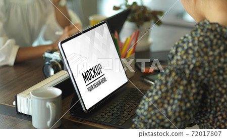 Side view of female hands working with tablet on worktable in meeting room 72017807