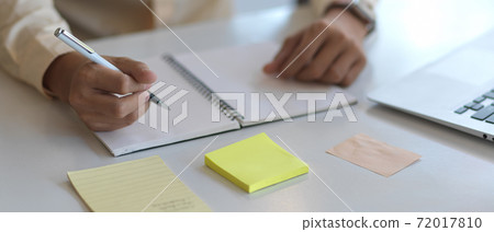 Close up view of male hand writing on blank notebook on white worktable 72017810