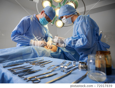 Doctors doing plastic surgery in operating room with medical instruments. 72017839