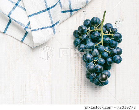 Dark grape bunch on white wooden table Dark grape bunch on white wooden table 72019778