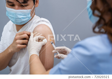 doctor holding syringe and using cotton before make injection to patient in medical mask. Covid-19 or coronavirus vaccine 72020321