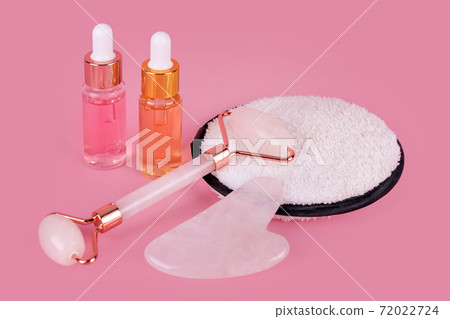 Jade face roller and Gua sha stone for facial massage. Home skin care anti-aging tools, face serum bottle, massage roller. Natural organic essential oil, skincare beauty product. 72022724