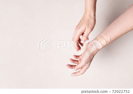 Female hands with smears of beige facial foundation, color test 72022752
