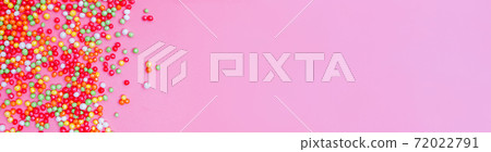 Decorative sugar sprinkles on a pink backdrop. 72022791