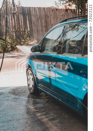 Self-service car wash, a person washes the foam from the car with water under high pressure. 72023121