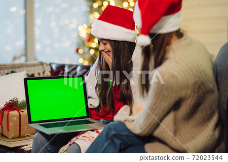 Two girls communicate via the Internet with friends. 72023544