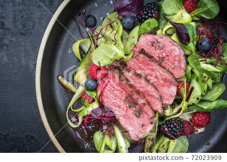 Traditional barbecue dry aged sliced filet steak with lettuce and forest fruits 72023909