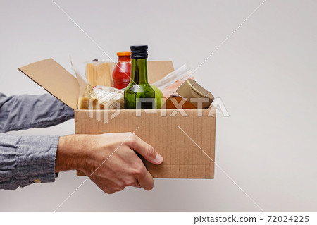 Man holding a box full on canned and packed foodstuff 72024225