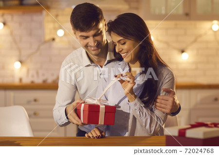 Young pretty woman unpacking holiday gift from her loving boyfriend or husband Young pretty woman unpacking holiday gift from her loving boyfriend or husband 72024768
