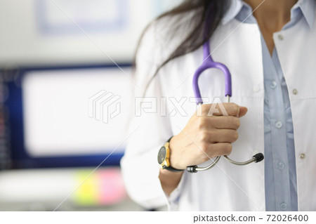 Doctor's hand holds stethoscope in medical office. Doctor's hand holds stethoscope in medical office. 72026400