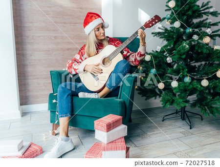 woman playing guitar at christmas woman playing guitar at christmas 72027518