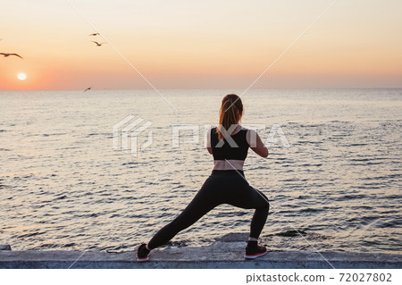 Young woman making exercises near the sea Young woman making exercises near the sea 72027802