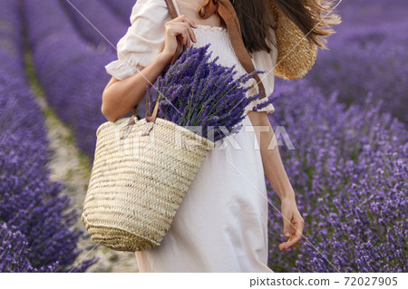 Woman holding wicker basket with lavender in the field 72027905