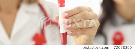 Doctors hold test tube with red blood in white coats with red ribbon on chest close-up 72028390