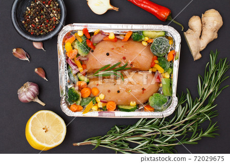 Raw chicken breasts or fillet in metal container with ingredients. Raw chicken breasts or fillet in metal container with ingredients. 72029675