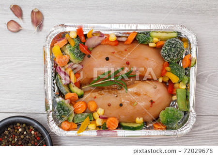 Raw chicken breasts or fillet in metal container with ingredients. Raw chicken breasts or fillet in metal container with ingredients. 72029678