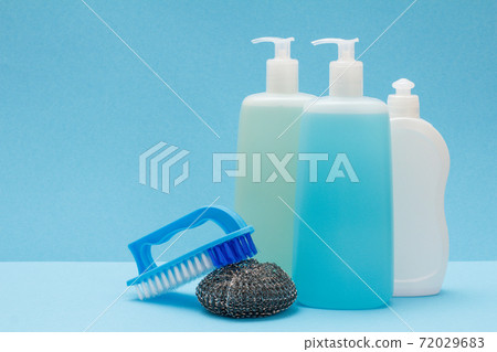 Bottles of dishwashing liquid, brush and sponge on blue background. Bottles of dishwashing liquid, brush and sponge on blue background. 72029683