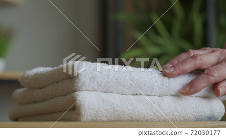 Old woman touches a fresh white towel Old woman touches a fresh white towel 72030177