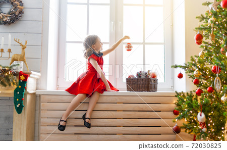 girl is decorating Christmas tree girl is decorating Christmas tree 72030825
