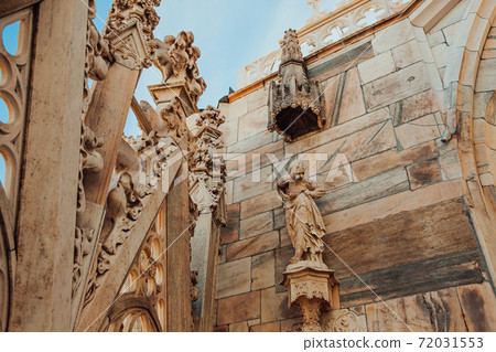 Roof of Milan Cathedral Duomo di Milano with Gothic spires and white marble statues. Top tourist attraction on piazza in Milan, Lombardia, Italy. Wide angle view of old Gothic architecture and art. 72031553