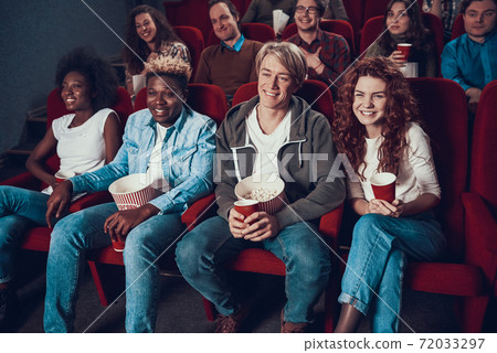 People in the front row sit and eat popcorn. Stock Photo