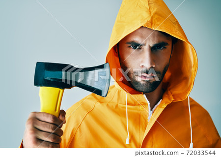 Portrait of brutal handsome man in bright raincoat holding big axe Portrait of brutal handsome man in bright raincoat holding big axe 72033544